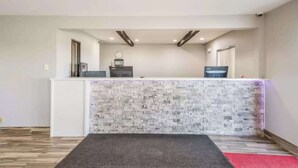 A reception area with a white counter, a clock, and a digital display. - Sonesta Essential Des Moines (Des Moines)
