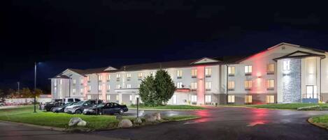 Un hôtel à plusieurs étages, doté d’un parking et d’une façade bien éclairée.