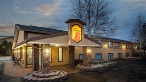 A Super 8 hotel with a stone facade, outdoor seating, and a well-lit entrance. - Super 8 by Wyndham Craig (Craig)