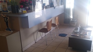 A reception area with a counter, chairs, a coffee table, and a floor mat with social distancing markings. - Super 8 by Wyndham Craig (Craig)