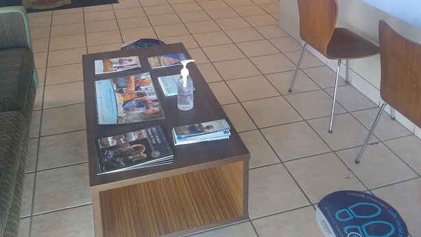 A hotel reception area with a counter, bar stools, a coffee station, and a seating area with a coffee table. - Super 8 by Wyndham Craig (Craig)