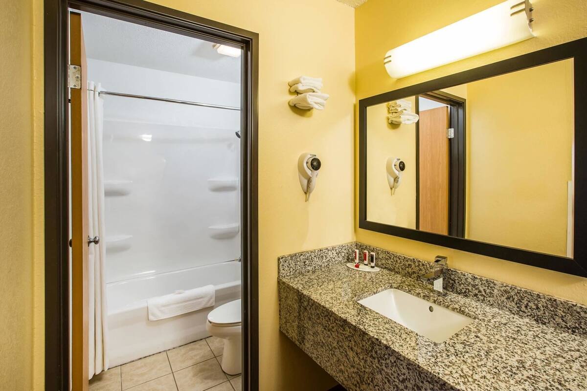 Une salle de bain équipée d’une douche, de toilettes, d’un lavabo et d’un miroir.
