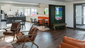 A modern hotel room with a kitchen, dining area, and seating space.