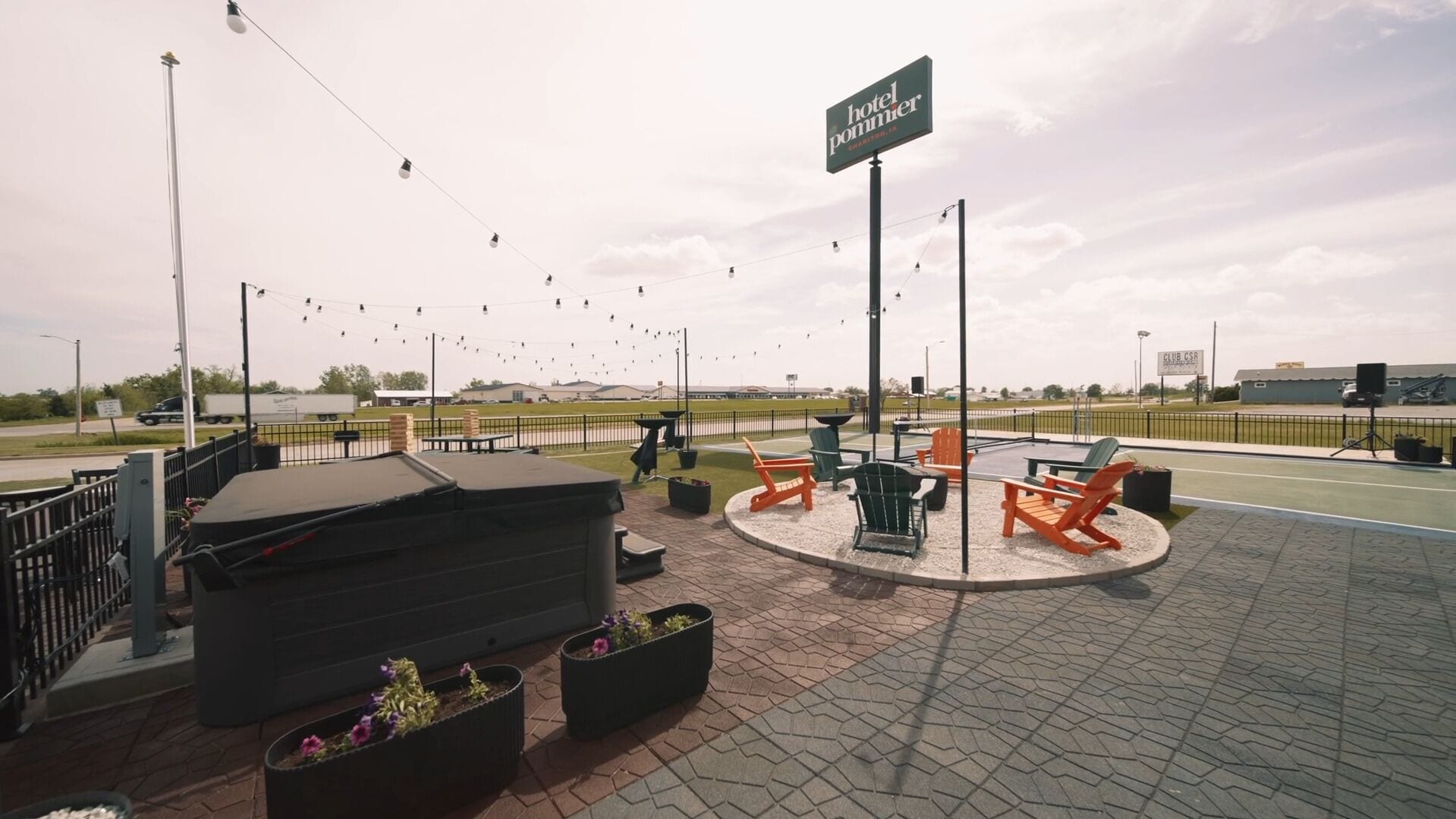 A patio area with outdoor seating, a sign for 'hotel pommer', and a view of a road with vehicles.