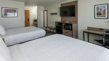 Ein Hotelzimmer mit zwei Betten, einer Mikrowelle, einem kleinen Schreibtisch und einem Fernseher.
