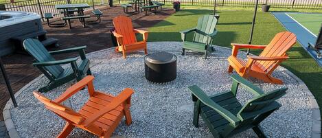 A circular seating area with Adirondack chairs and a fire pit.