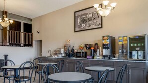 A hotel kitchen with a coffee station, a refrigerator, and a framed welcome sign. - Super 8 by Wyndham Clinton (Clinton)