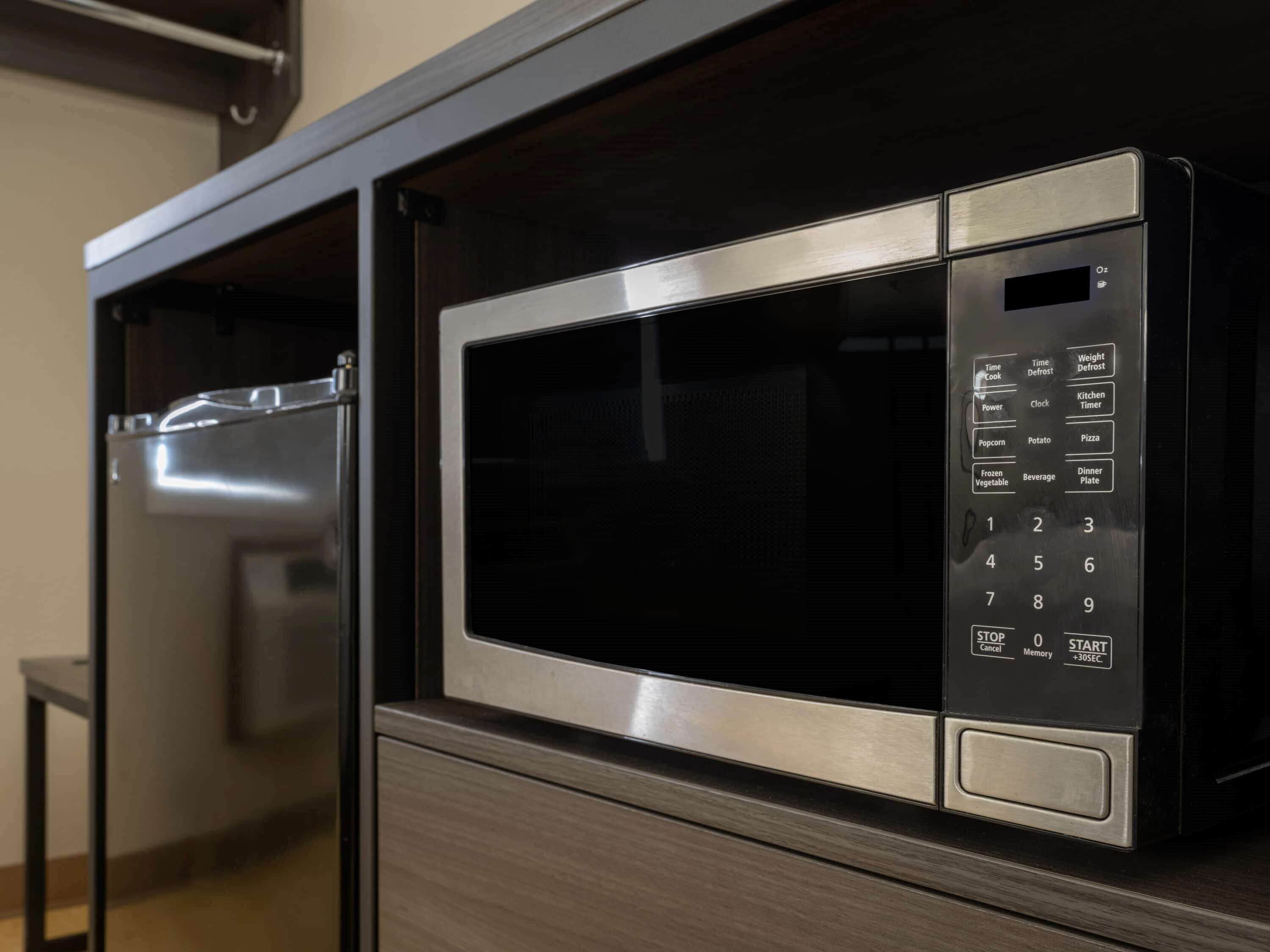 Un horno microondas con panel de control digital, integrado en un mueble.