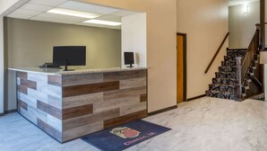 A reception area with a counter, a chandelier, a staircase, and a doormat with a logo. - Super 8 by Wyndham Clinton (Clinton)