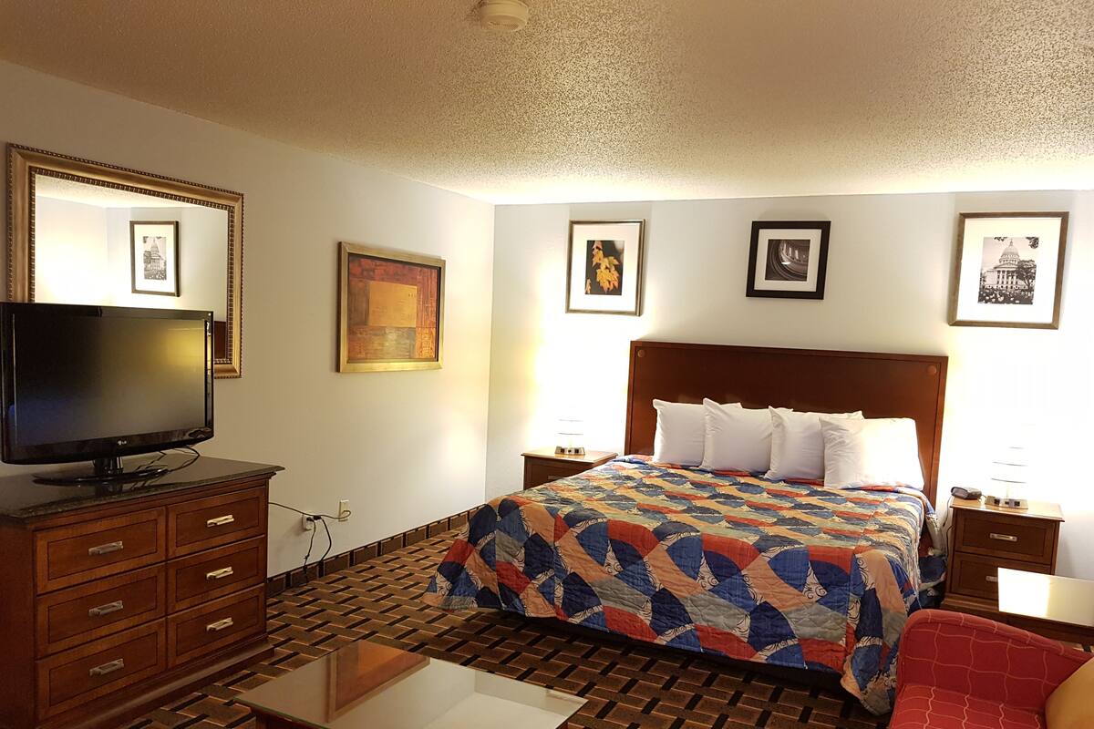 A hotel room with a bed, a television, a desk, and a chair.