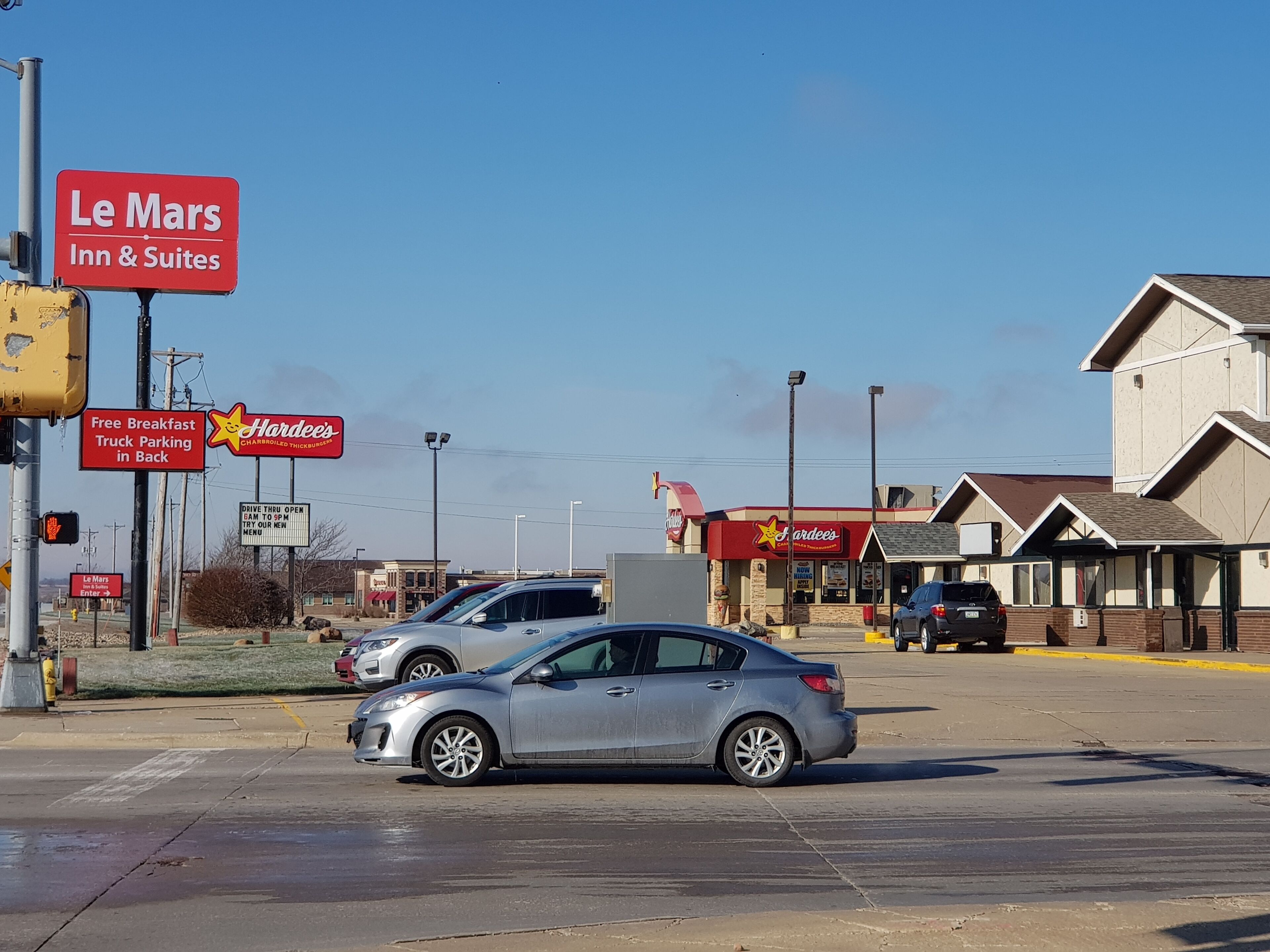 A parking lot with a sign for Le Mars Inn & Suites and Hardee's.