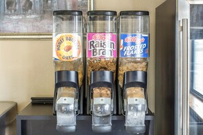 Three condiment dispensers with labels for Honey Buns of Oats, Raisin Bran, and Frosted Flakes. - Le Mars Inn & Suites (Le Mars)