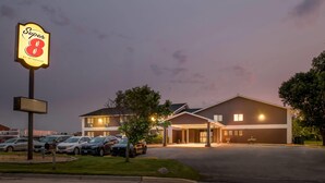 A hotel with a large sign reading "Super 8" and a parking lot with several cars.