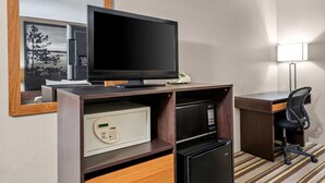 Een hotelkamer met een flatscreen televisie, een minibar, een magnetron, een bureau, een stoel en een lamp.