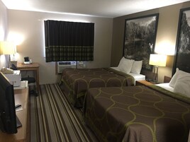 A hotel room with two beds, a desk, a chair, a television, and a window with curtains.