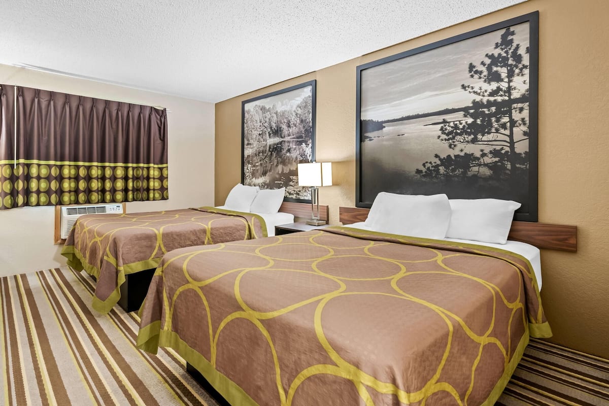 Une chambre d’hôtel avec deux lits, une grande fenêtre donnant sur un lac et une moquette à rayures.