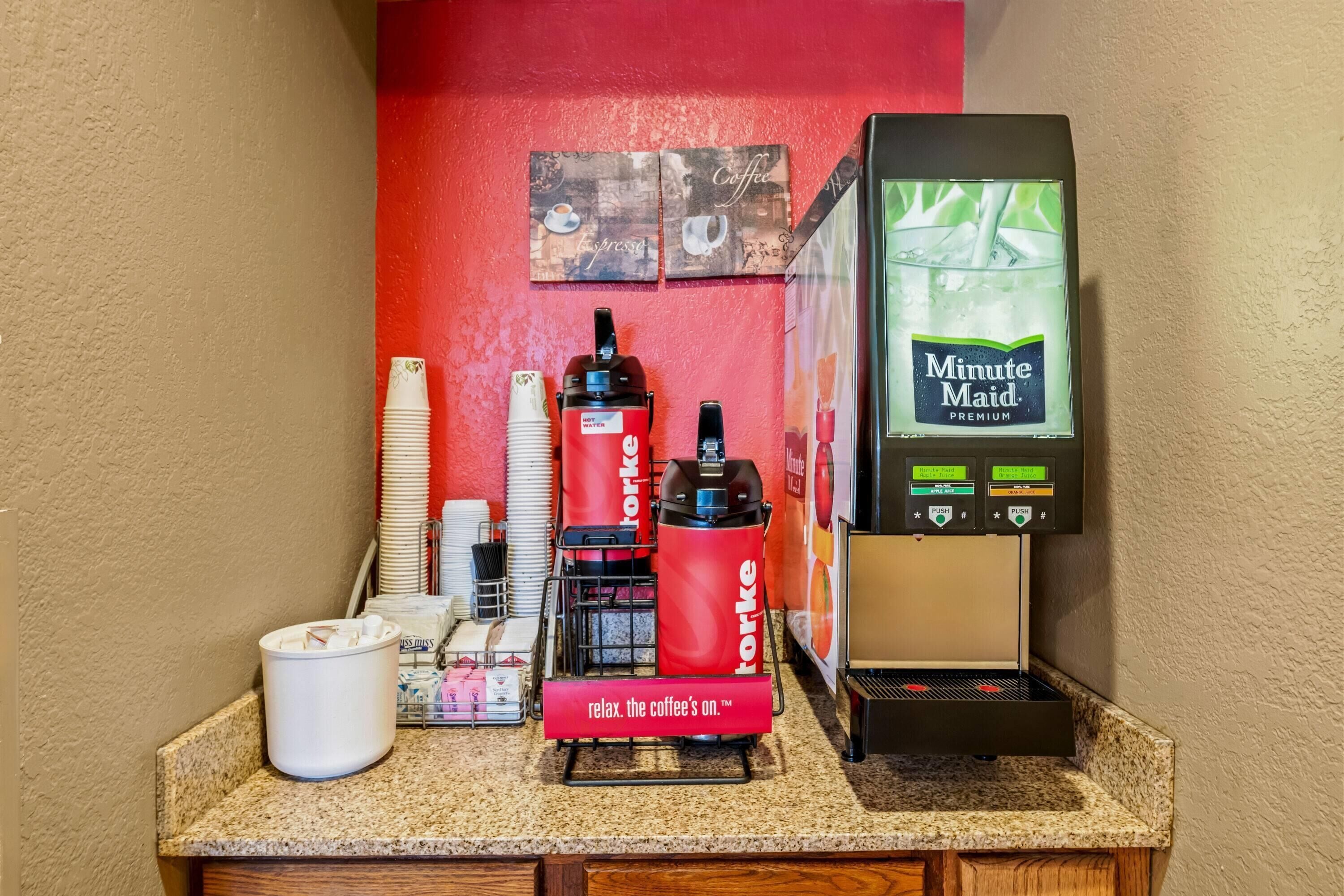 Una estación de café con una máquina de café, dispensador de agua caliente y una botella de agua.
