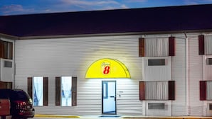 A Super 8 motel with a prominent yellow arch sign, a white exterior, and a single visible door. - Super 8 by Wyndham Columbus (Columbus)