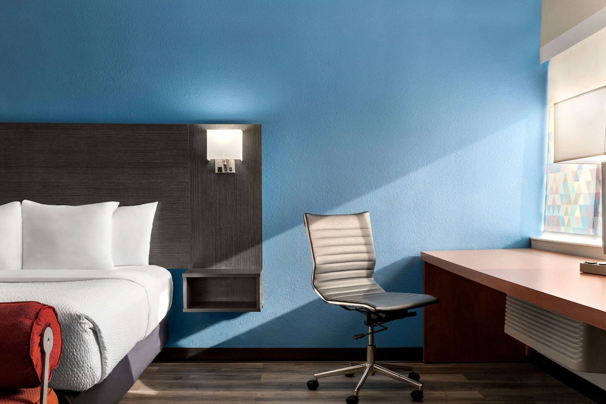 Una habitación de hotel con cama, escritorio y silla.