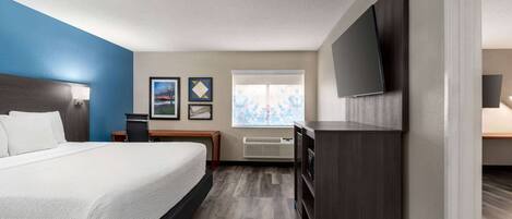 A hotel room with a bed, a desk, a flat-screen TV, and a window with a view.