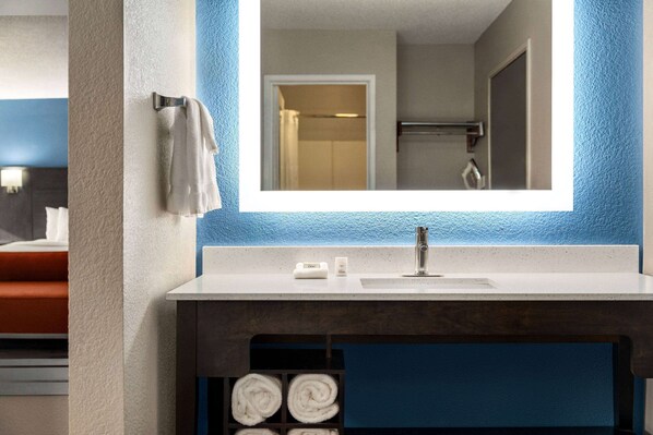 Un baño con lavamanos blanco, un espejo y un perchero para toallas.