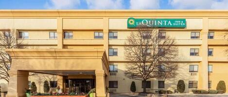 Edificio de La Quinta Inn & Suites con fachada color crema, un acceso cubierto y un estacionamiento.