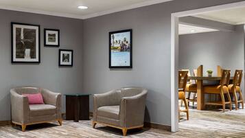 A room with two leather armchairs, a dining table with chairs, and framed pictures on the walls.