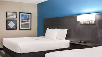 A hotel room with a bed, bedside table, and wall-mounted lamp.