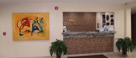 A reception desk with a 'Baymont' sign, a fire alarm, and a large abstract painting.