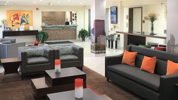 A modern lobby with sofas, tables, and a reception desk.