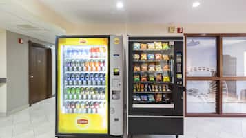 Dos máquinas expendedoras en un vestíbulo, una con bebidas y la otra con aperitivos.