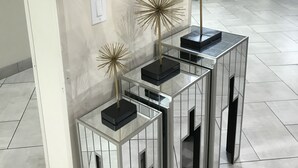 A modern interior with a flat-screen TV displaying a menu, decorative golden star-shaped objects on mirrored stands, and a tiled floor.