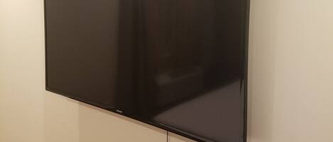 A flat-screen TV mounted on a plain wall in a room with a carpeted floor.