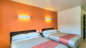 Une chambre d’hôtel avec deux lits, des murs orange et des lampes fixées au mur.