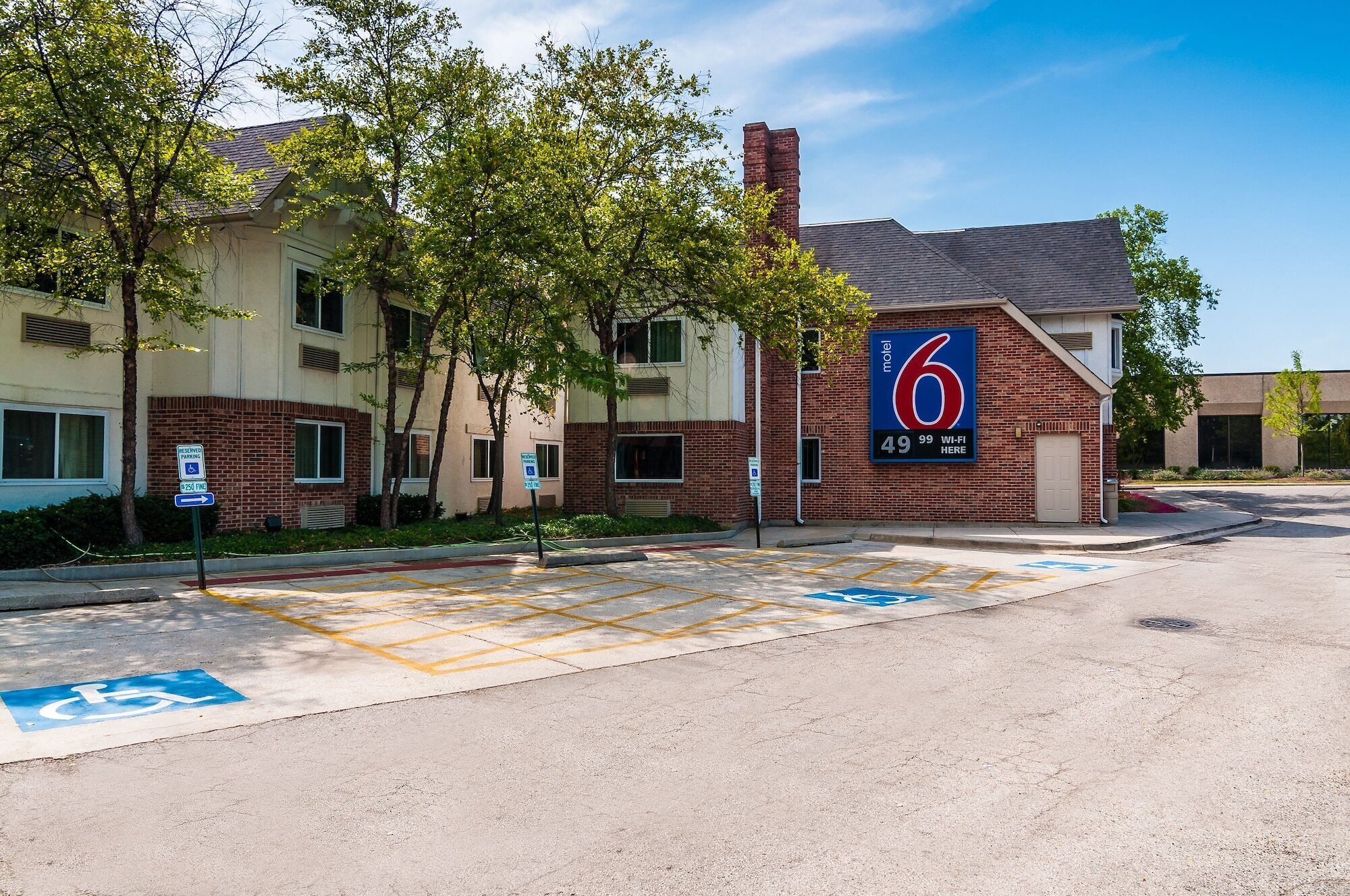 A motel with a large sign, reserved parking, and a handicap parking space.