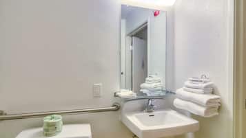 Een badkamer met een wit wastafelmeubel, een spiegel, een toilet en een handdoekhouder.