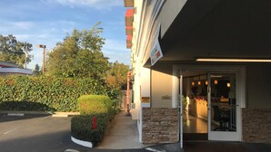 Ein Hotel mit einer Steinfassade, einer Glastür und einer kleinen Steinmauer.