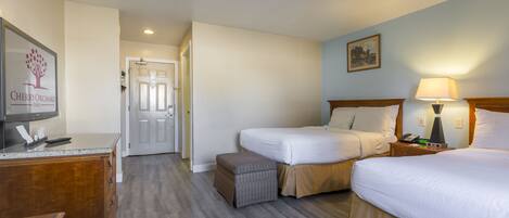 Une chambre d’hôtel avec deux lits, un bureau, une télévision et une lampe.