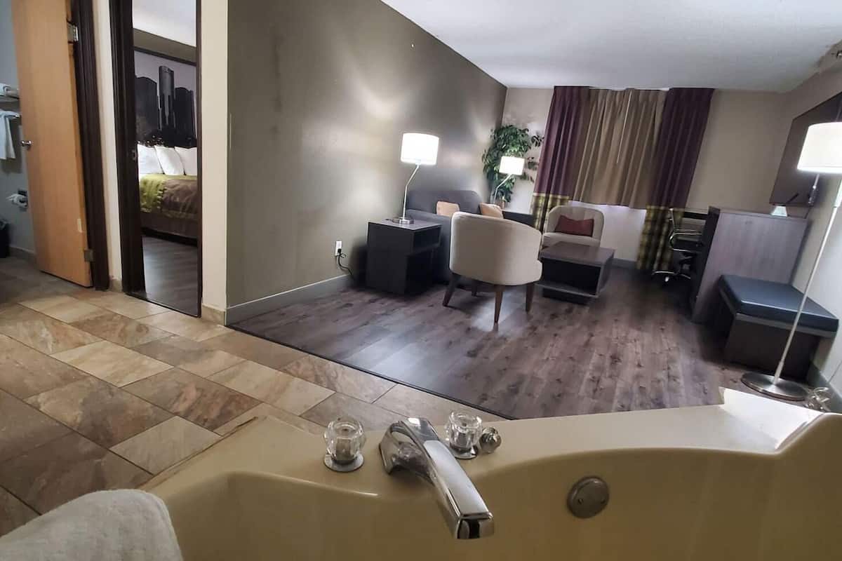 Ett hotellrum med badrum, ett vardagsrum med soffa och TV samt en matplats med bord och stolar.