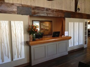 A reception desk with a laptop, a vase with flowers, and a framed picture on the wall.