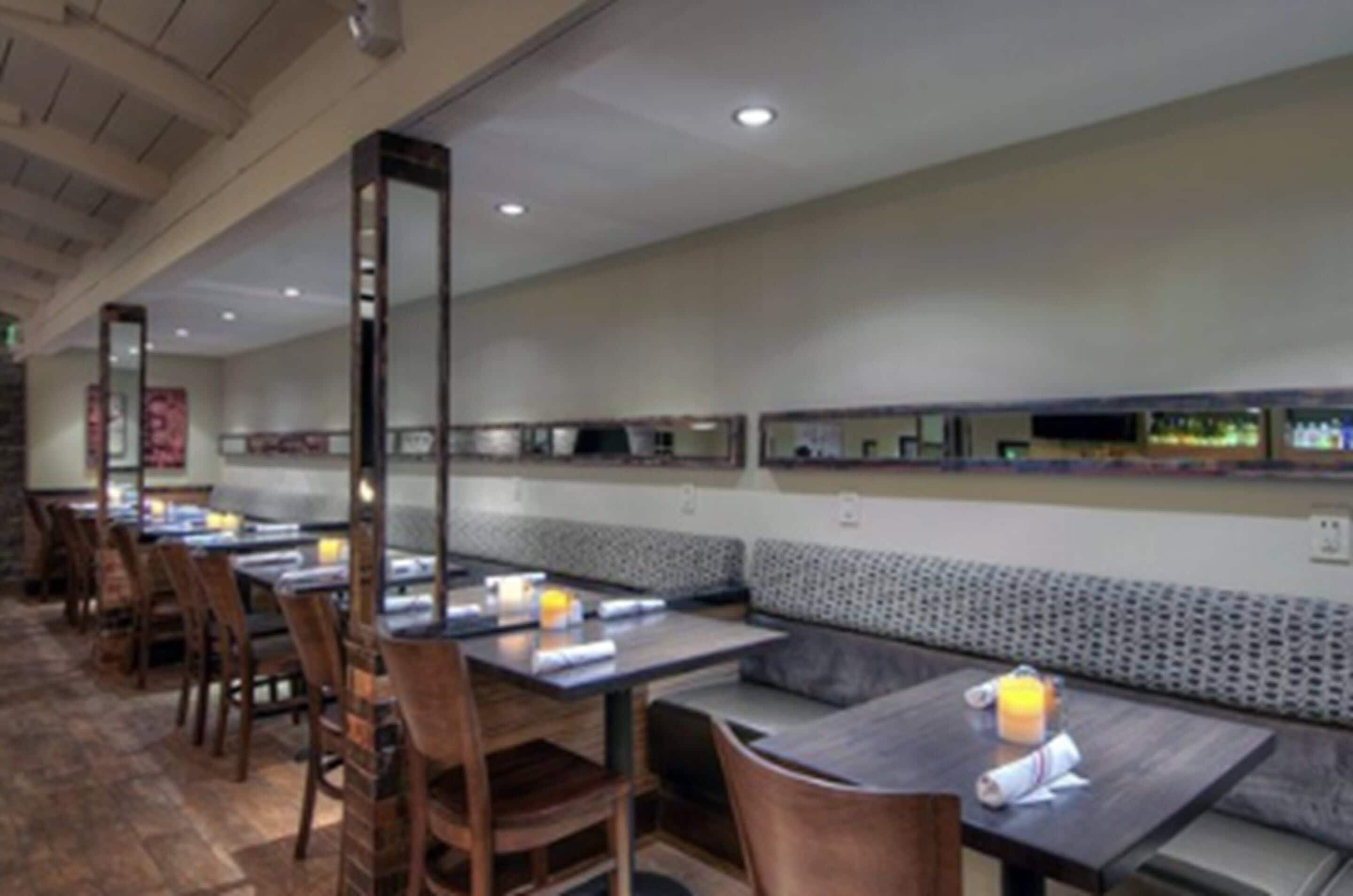 A restaurant with long tables and booths, wooden chairs, and a patterned wall.
