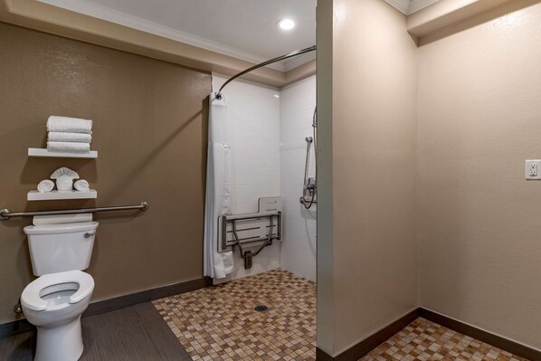 A bathroom with a toilet, a shower with a grab bar, and a tiled floor.