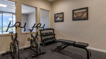 Une salle de sport équipée de vélos d’appartement, d’haltères et d’un banc de musculation.