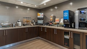Una cocina moderna con un área de autoservicio, que incluye una máquina de café, un dispensador de yogur y un microondas.