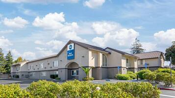 A hotel with a sign indicating it is part of the Best Western chain, featuring a parking lot and well-maintained landscaping.