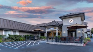 Un hall de hotel con un reloj, asientos al aire libre y un estacionamiento.