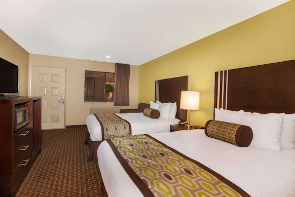 A hotel room with two beds, a television, a desk, and a window with curtains. - Days Inn by Wyndham San Jose Airport (Milpitas)
