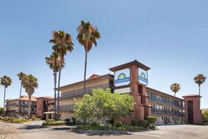 Un hotel Days Inn con techo de tejas rojas, varios balcones y palmeras.