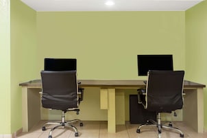 A room with two desks, each with a computer monitor and a black office chair.