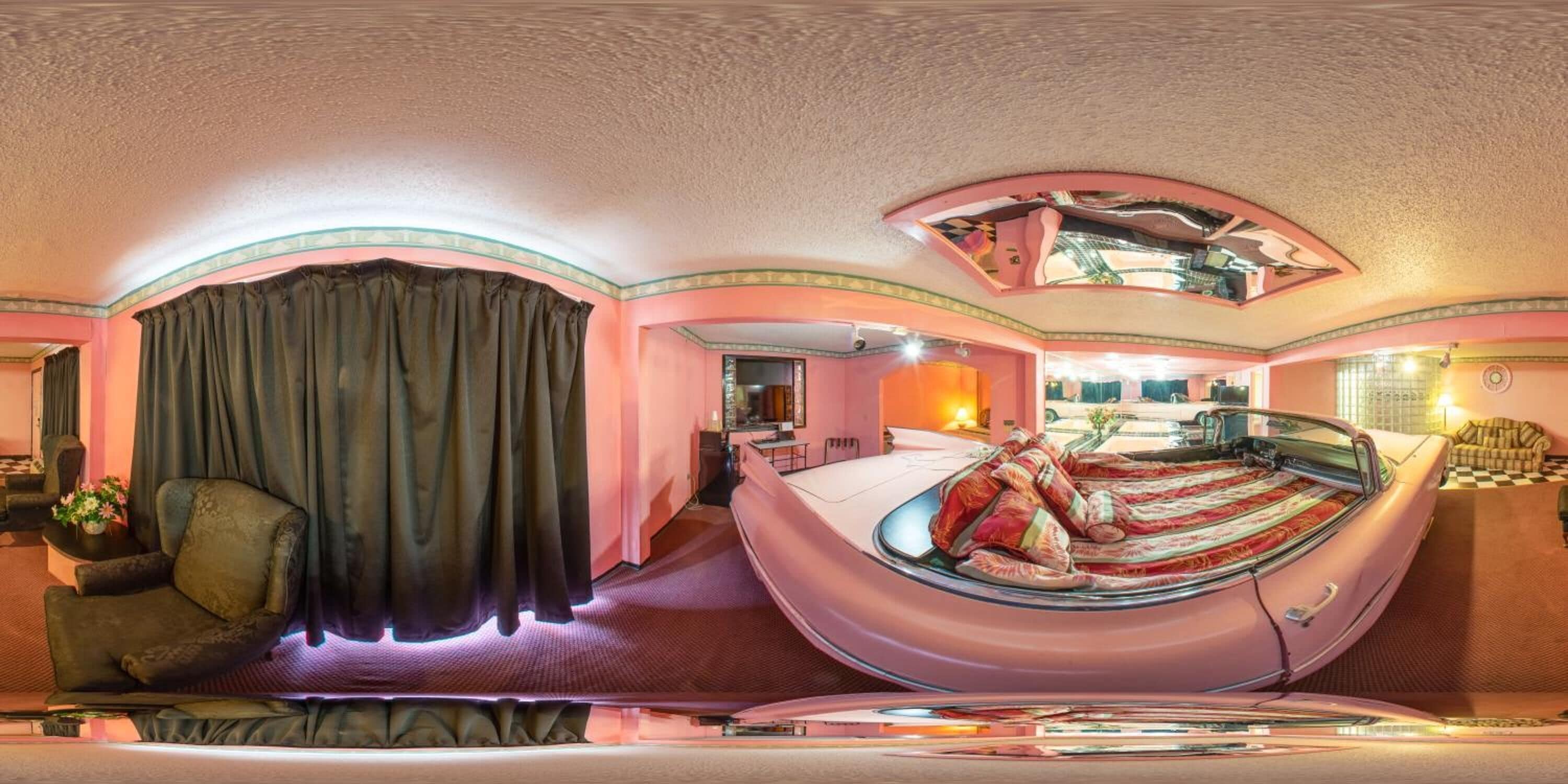 A room with a bed, a chair, and a desk. There is a window with curtains.